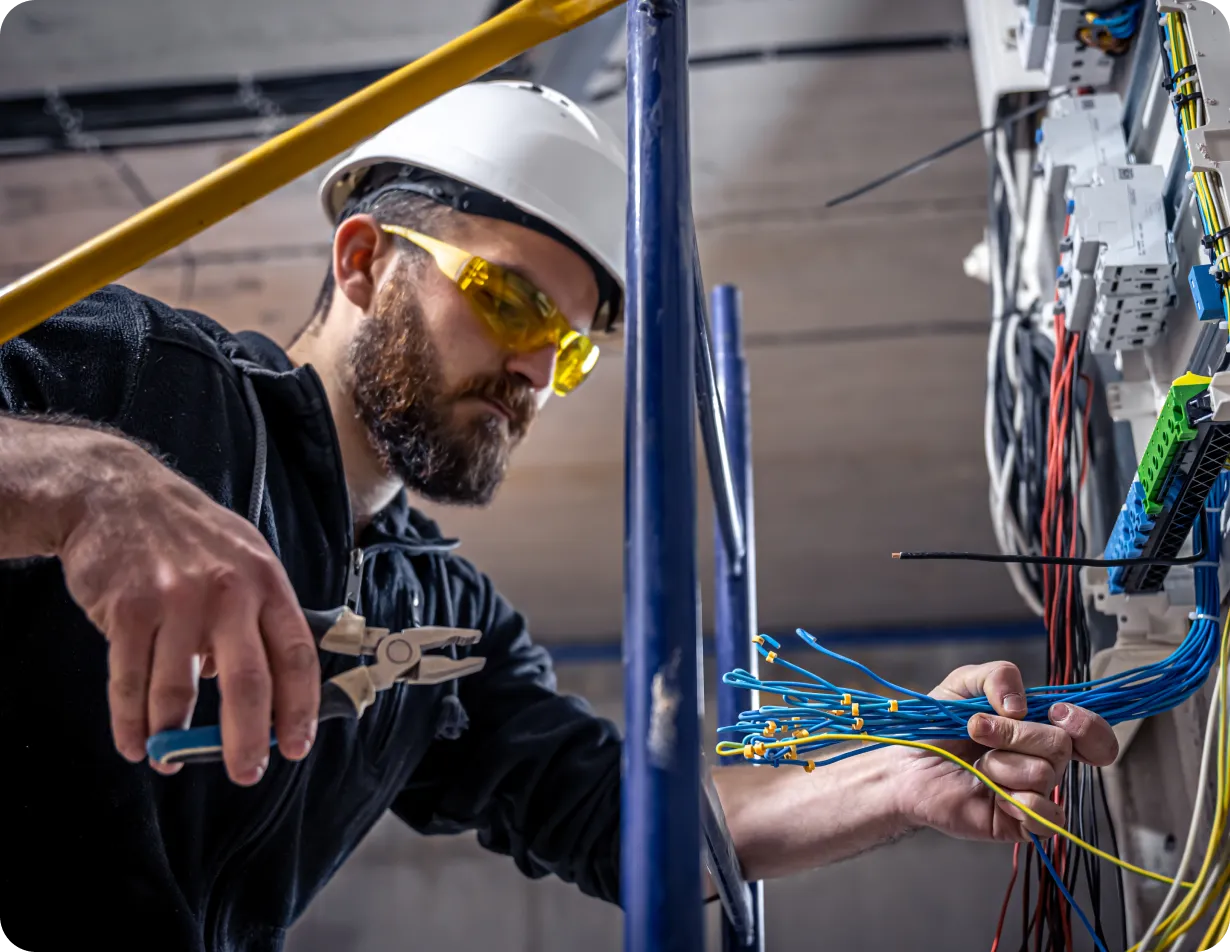 Electrician working on electrical wiring panel.